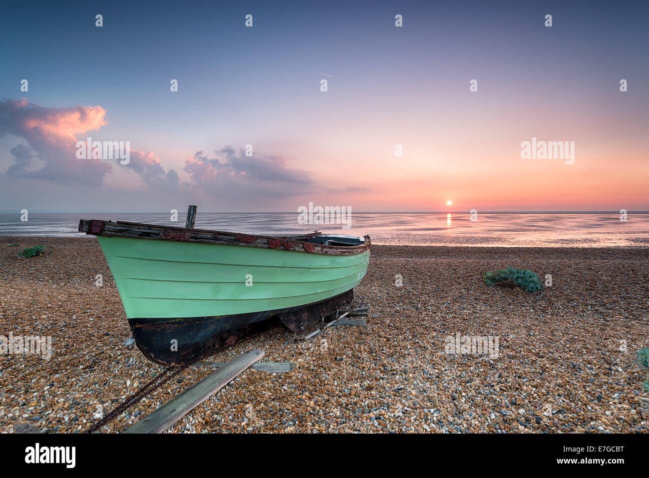 Bateau de pêche vert au lever du soleil sur une plage de galets à Lydd sur mer dans le Kent Banque D'Images