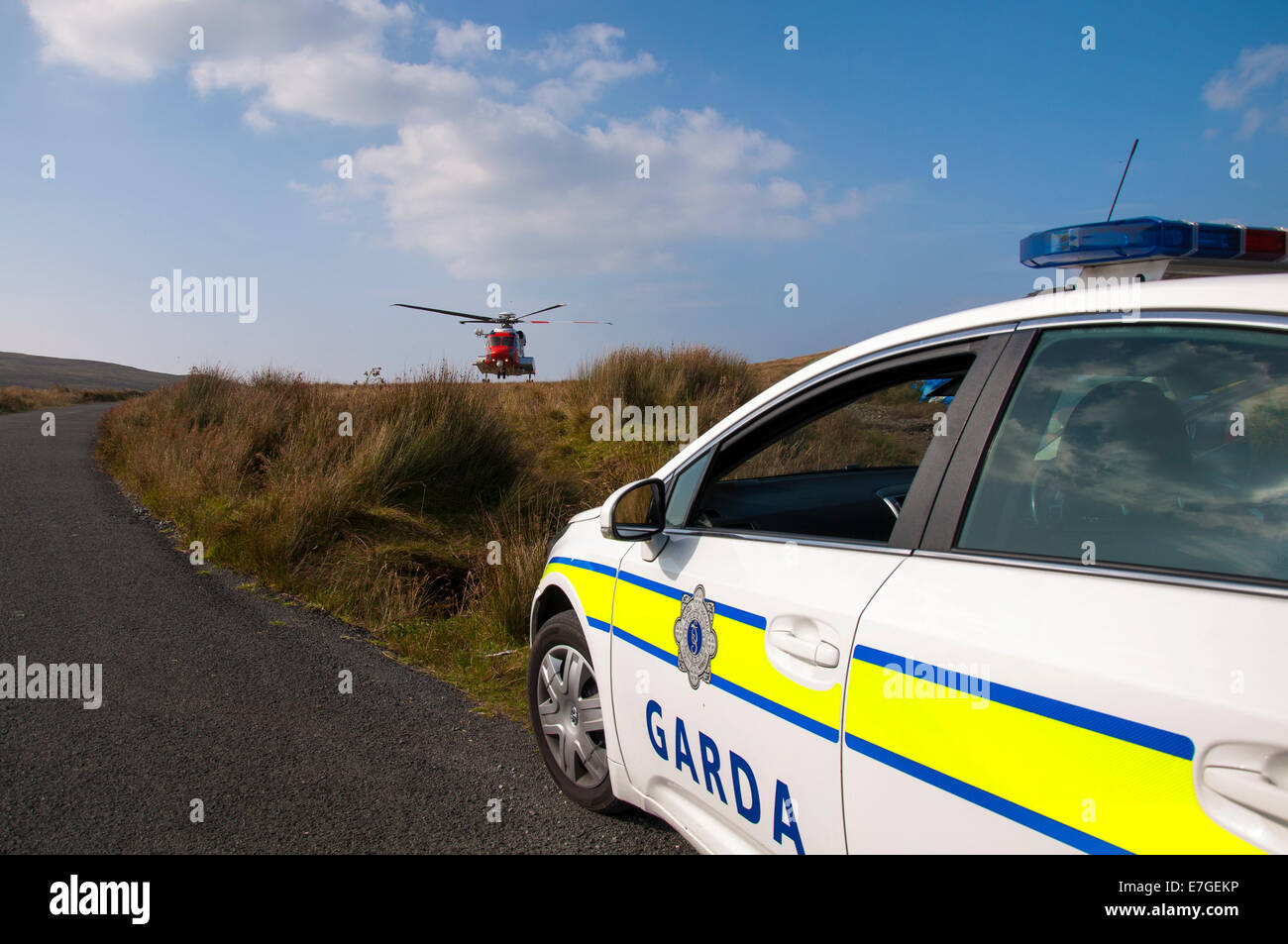 La Garde côtière irlandaise IRCG Garda Cósta na hÉireann hélicoptère Sikorsky vole au-dessus d'une voiture de police irlandais lors d'un secours médical Banque D'Images