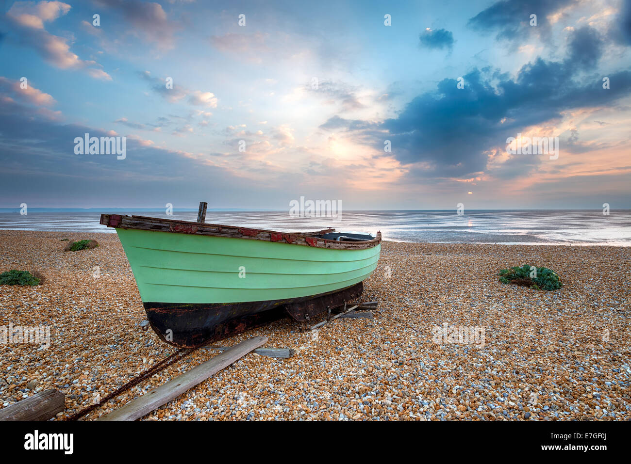 Bateau de pêche vert au lever du soleil sur une plage de galets à Lydd sur mer dans le Kent Banque D'Images