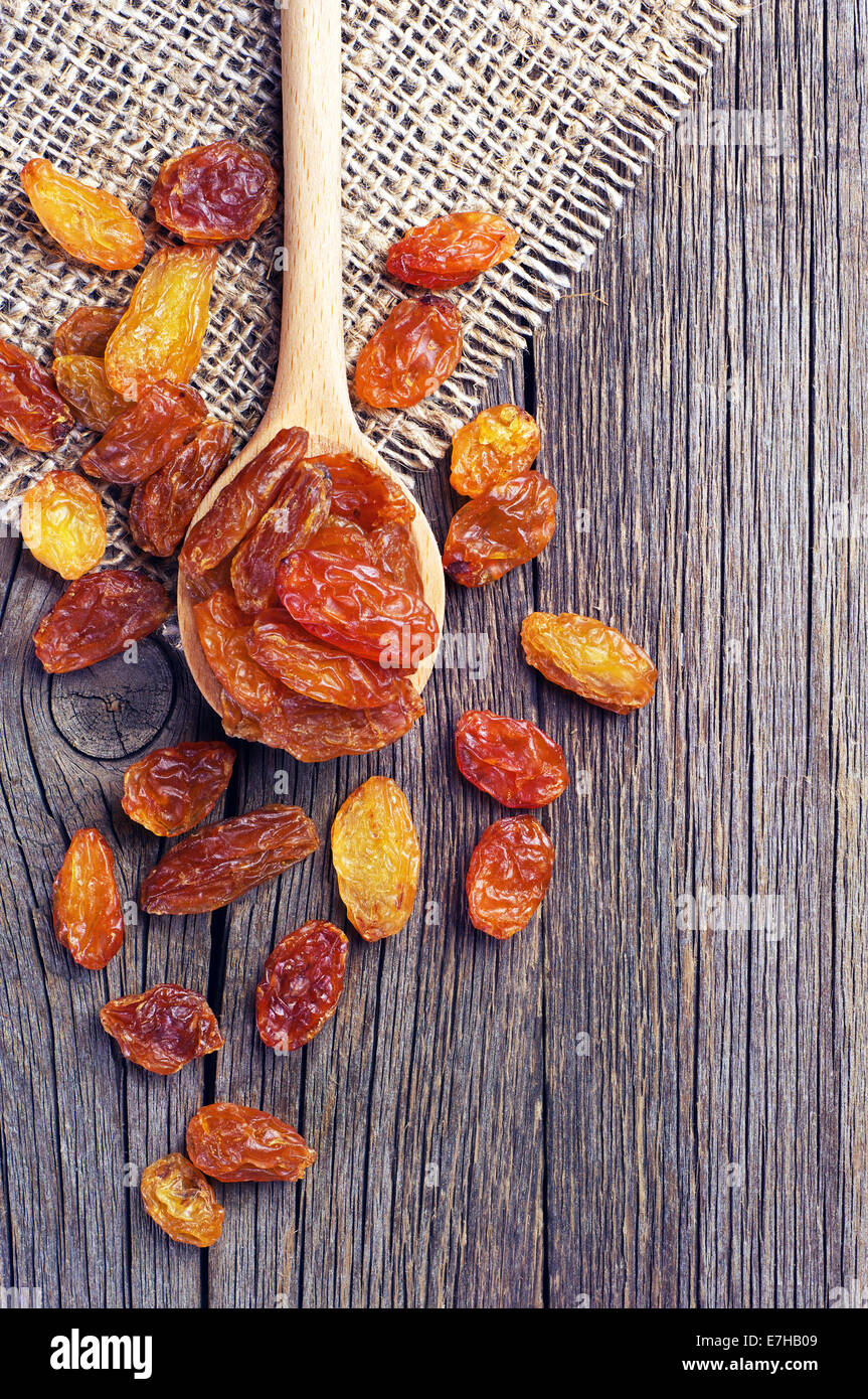 Les raisins secs dans une cuillère en bois sur fond de bois vintage Banque D'Images