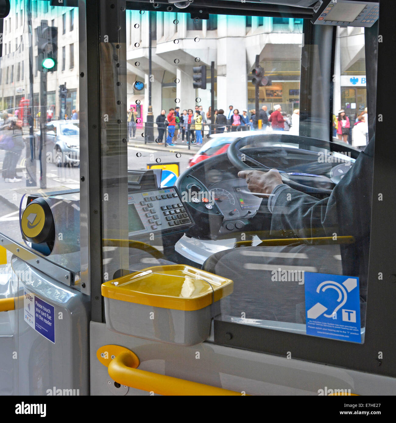 London bus driver au travail la conduite à droite à l'intérieur de la cabine du volant avec Oyster card reader et pictogramme audience England UK Banque D'Images