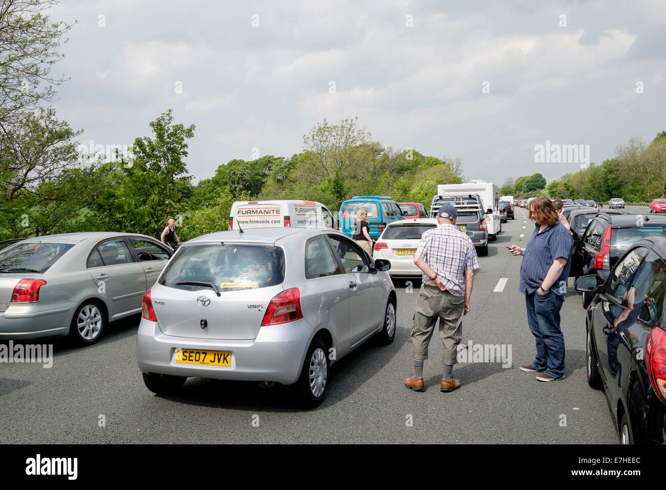 Personnes se tenant sur la chaussée à l'extérieur des véhicules stationnaires dans un embouteillage sur l'autoroute M6 en raison d'un accident causant un long retard. Angleterre Royaume-Uni Banque D'Images