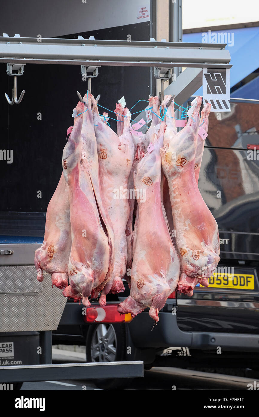 Viande suspendues à l'arrière d'un camion qu'une livraison est effectuée à une boucherie sur la rue principale à Stratford. Banque D'Images
