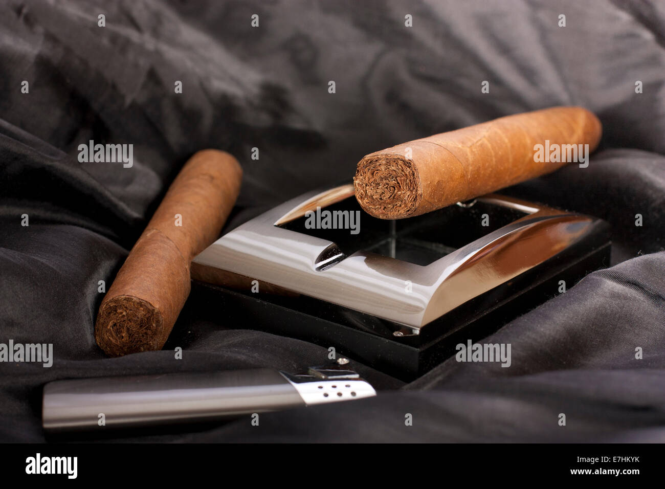 Close up of metallic cendrier, briquet et cigare cubain sur fond de soie noire Banque D'Images