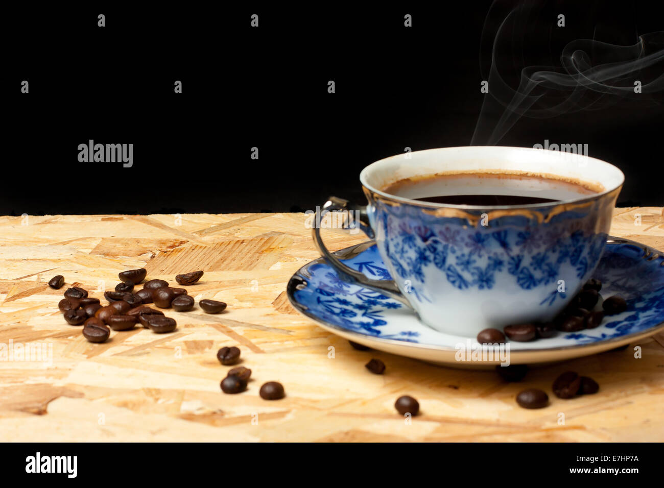 Une tasse de café et des haricots sur une table en bois avec fond noir Banque D'Images