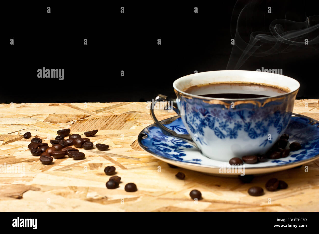Une tasse de café et des haricots sur une table en bois avec fond noir Banque D'Images