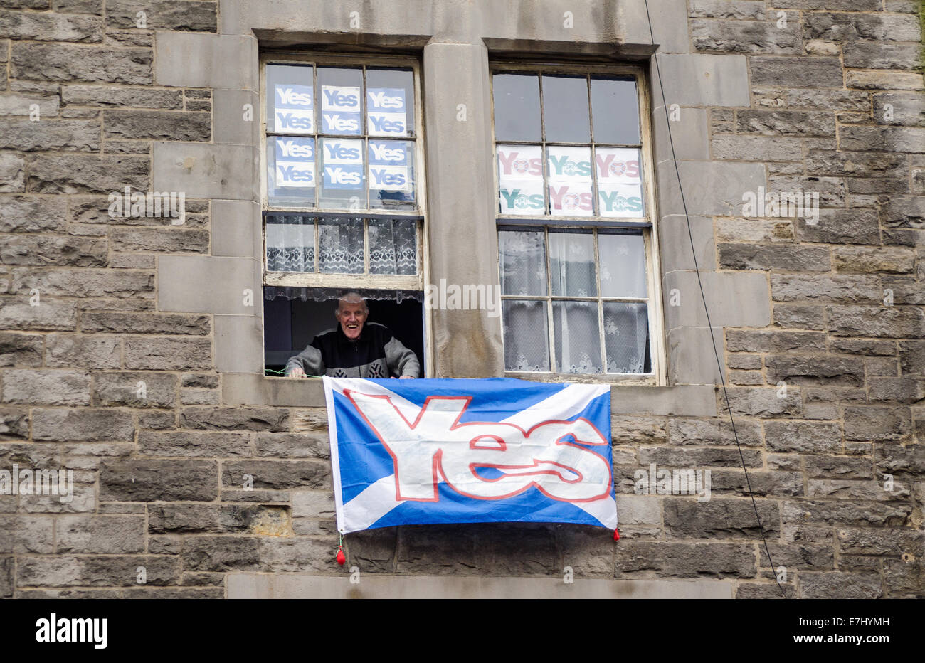 Édimbourg, Écosse, 11 septembre 2014 : Un homme âgé smiling à partir de la fenêtre de son appartement avec Édimbourg Oui des affiches. Banque D'Images
