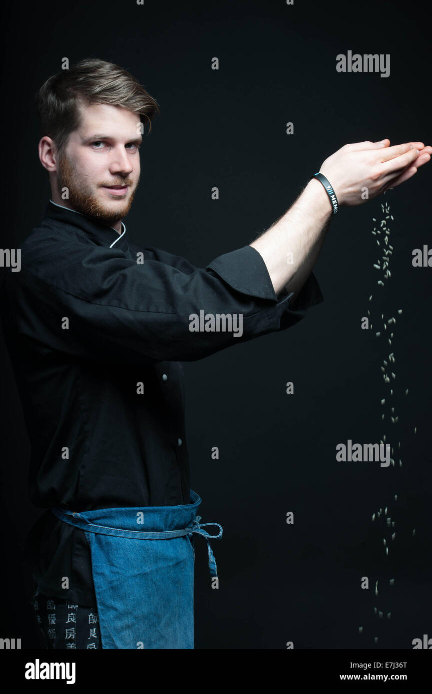 Jeune chef laissant tomber le riz de ses mains au cours de stylisme photo Banque D'Images