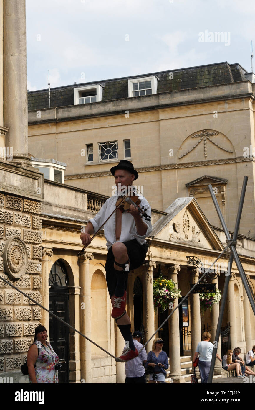 Homme marchant sur la corde serrée tout en jouant du violon, Busker / Street Entertainer dans le centre-ville de Bath Angleterre Royaume-Uni Banque D'Images Homme marchant sur la corde serrée tout en jouant du violon, Busker / Street Entertainer dans le centre-ville de Bath Angleterre Royaume-Uni Banque D'Images