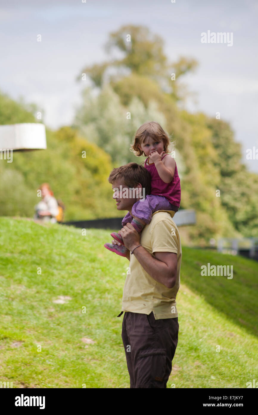 Homme portant une jeune fille assise sur les épaules à Caen Hill Locks, Kennet et Avon Canal, Devozes, Wiltshire, Angleterre, Royaume-Uni en août Banque D'Images