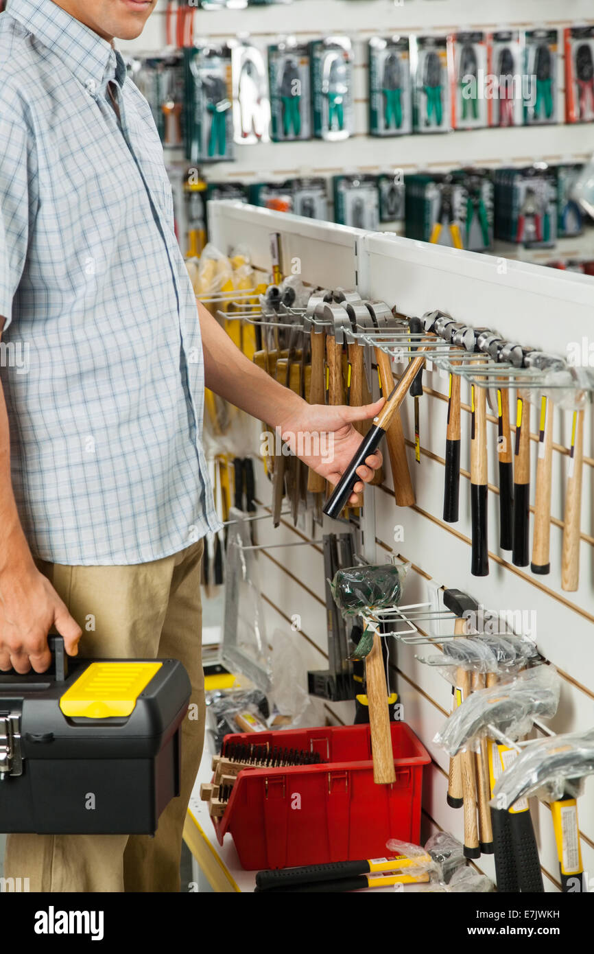 L'homme examinant hammer in hardware store Banque D'Images