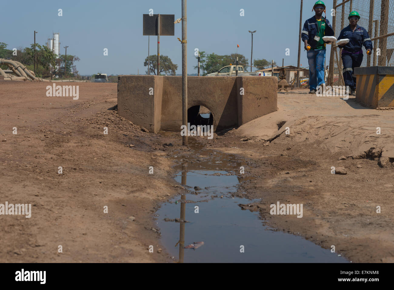 Deux travailleurs de la mine à pied le long d'un drain ouvert dans une usine d'enrichissement en cuivre. Banque D'Images