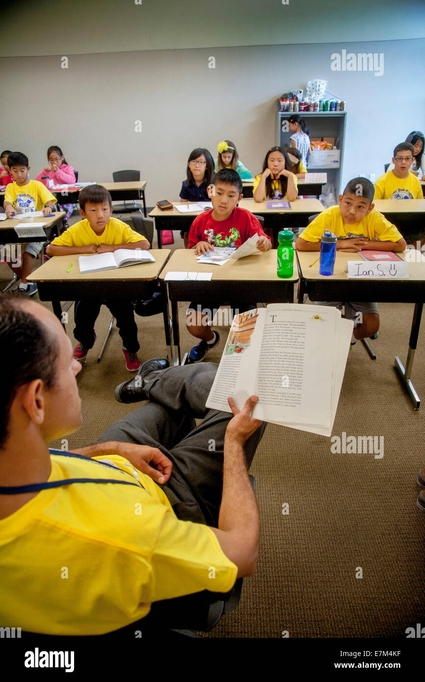 Les élèves de collège multiethnique comme écouter un enseignant lit 'les voyages de Gulliver' à haute voix à un atelier d'apprentissage d'été à Irvine, CA. Remarque T shirts jaune. Banque D'Images