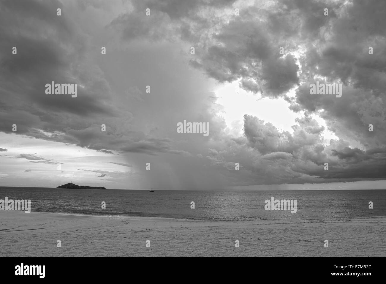 Ciel d'orage spectaculaire sur l'océan sur une plage solitaire en noir et blanc Banque D'Images
