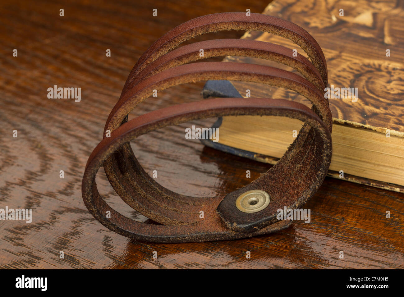Bracelet cuir fait main avec sur le vieux bois et un livre Banque D'Images