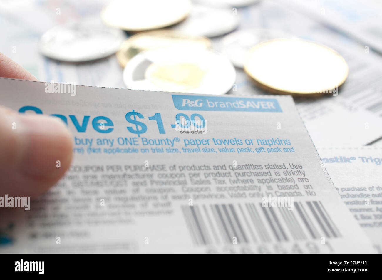 Coquitlam, BC Canada - Juillet 22, 2014 : Tenue d'économie canadienne coupons avec de l'argent. Tous les coupons de magasin canadien, ils ont trait à une question Banque D'Images