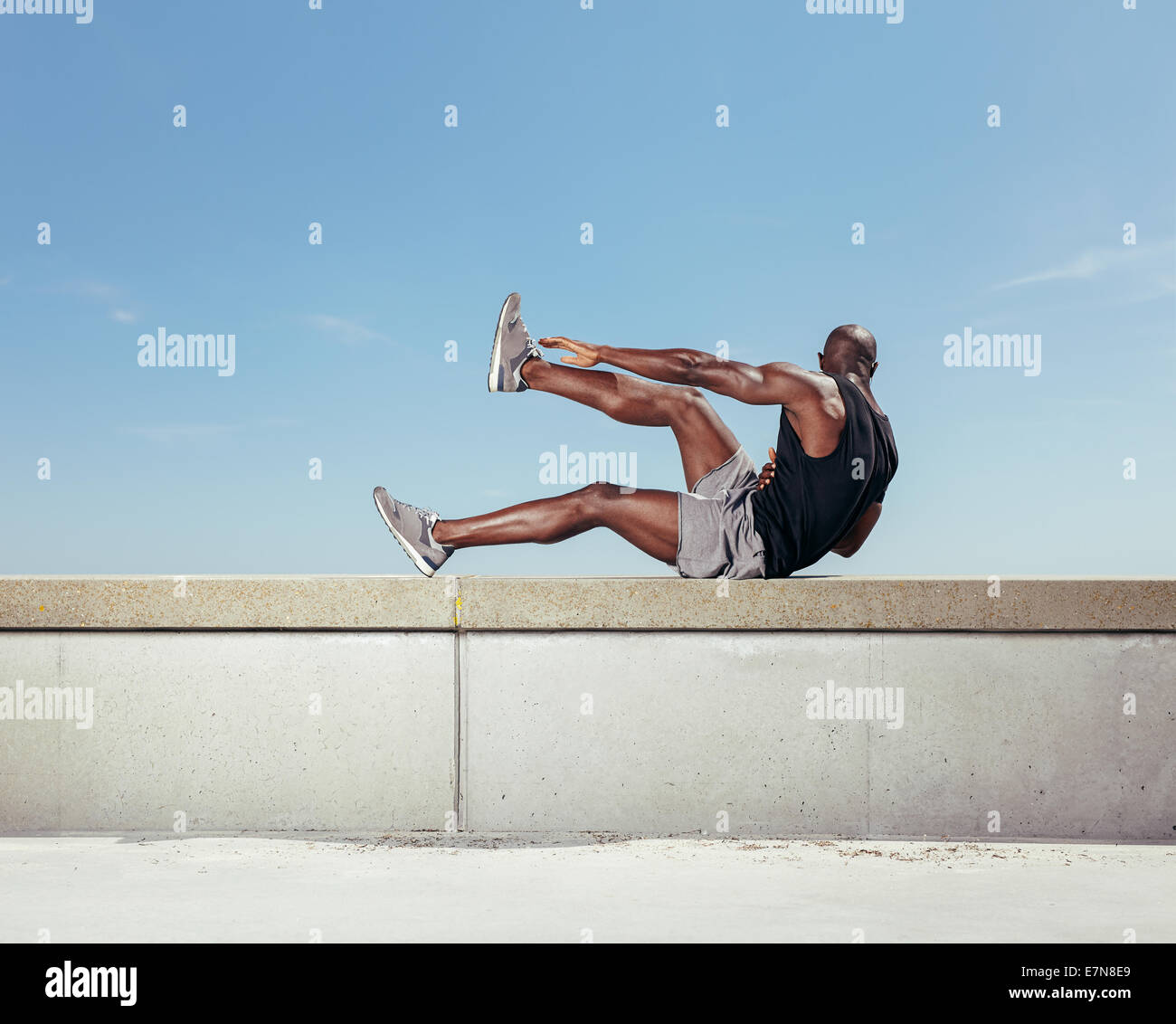 Jeune homme fort de l'exercice en plein air. Les jeunes de travail sur le modèle de remise en forme musculaire contre ciel. Banque D'Images