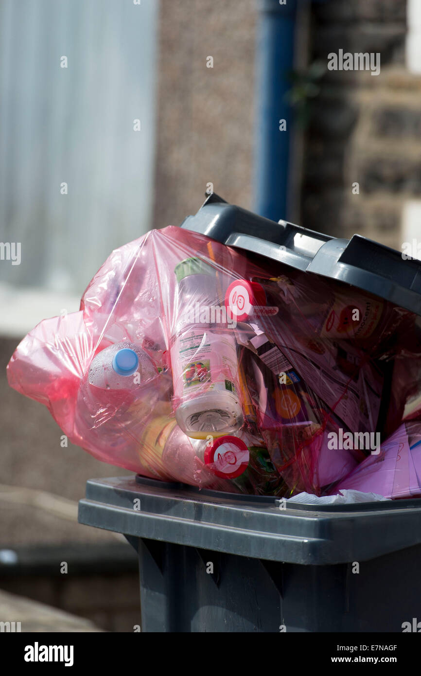 Un bac de recyclage vert surchargé pleine de détritus dans Cardiff, Galles du Sud. Banque D'Images
