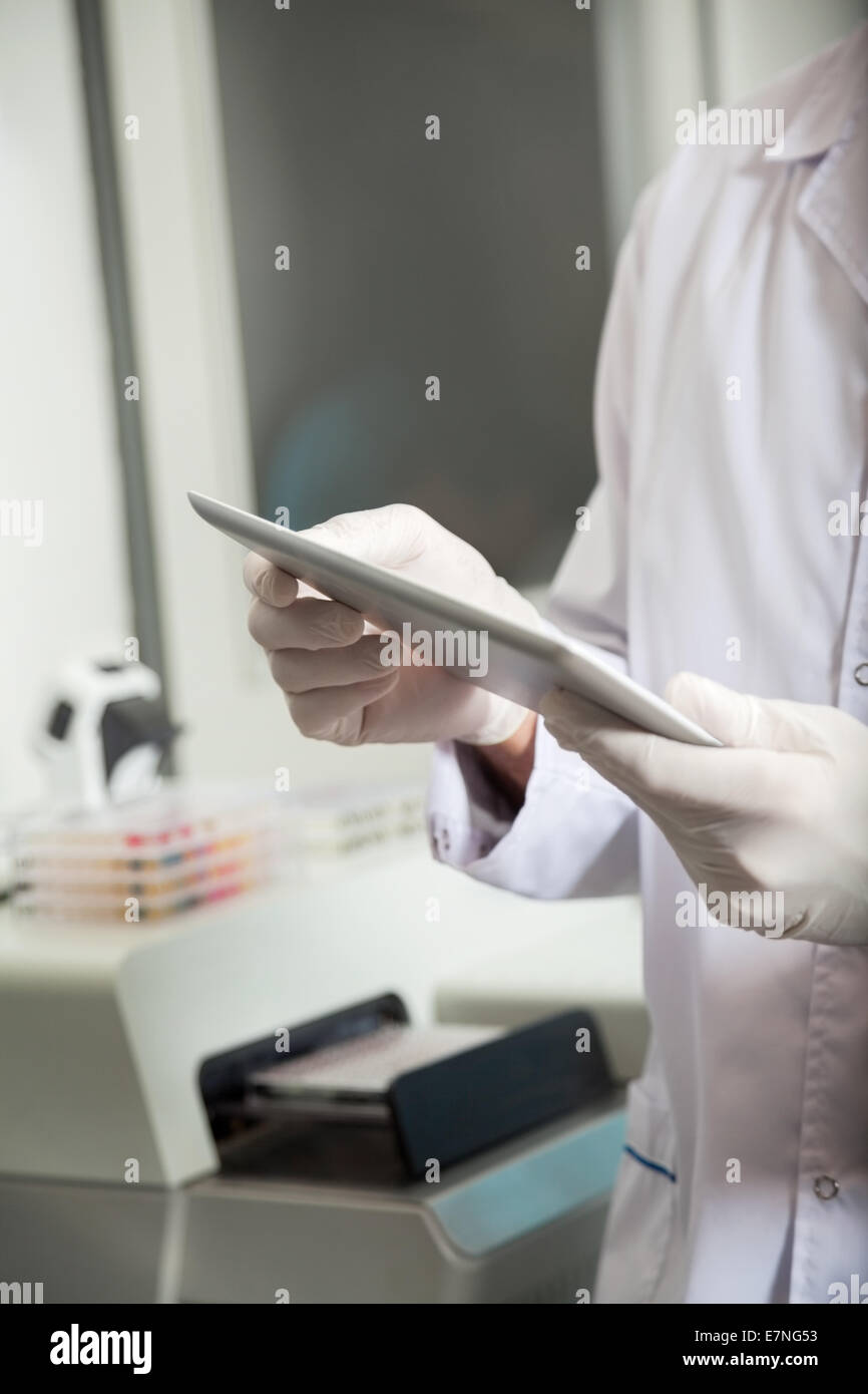 Technician using digital tablet in medical lab Banque D'Images