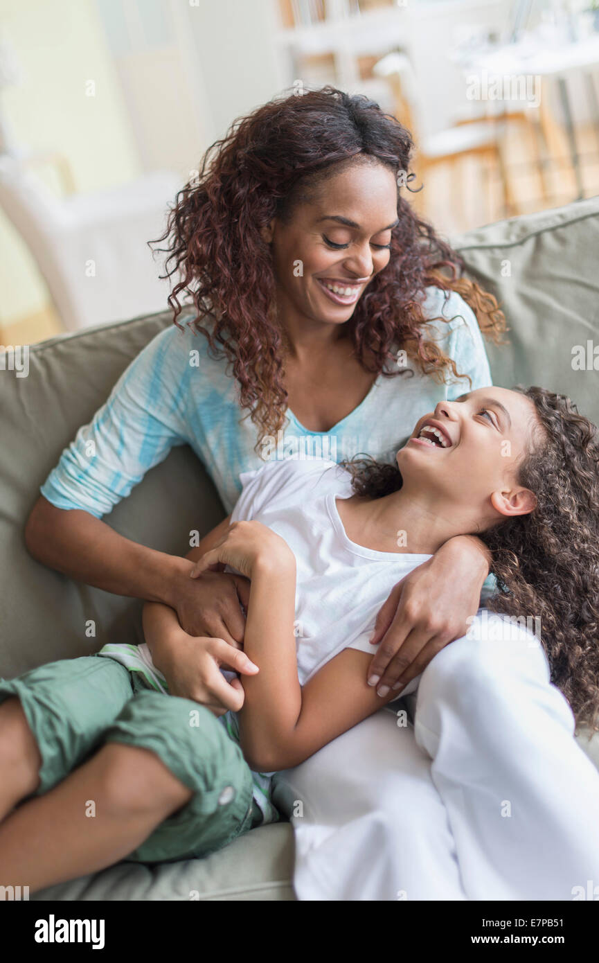 Mère fille tickling (8-9) sur canapé Banque D'Images