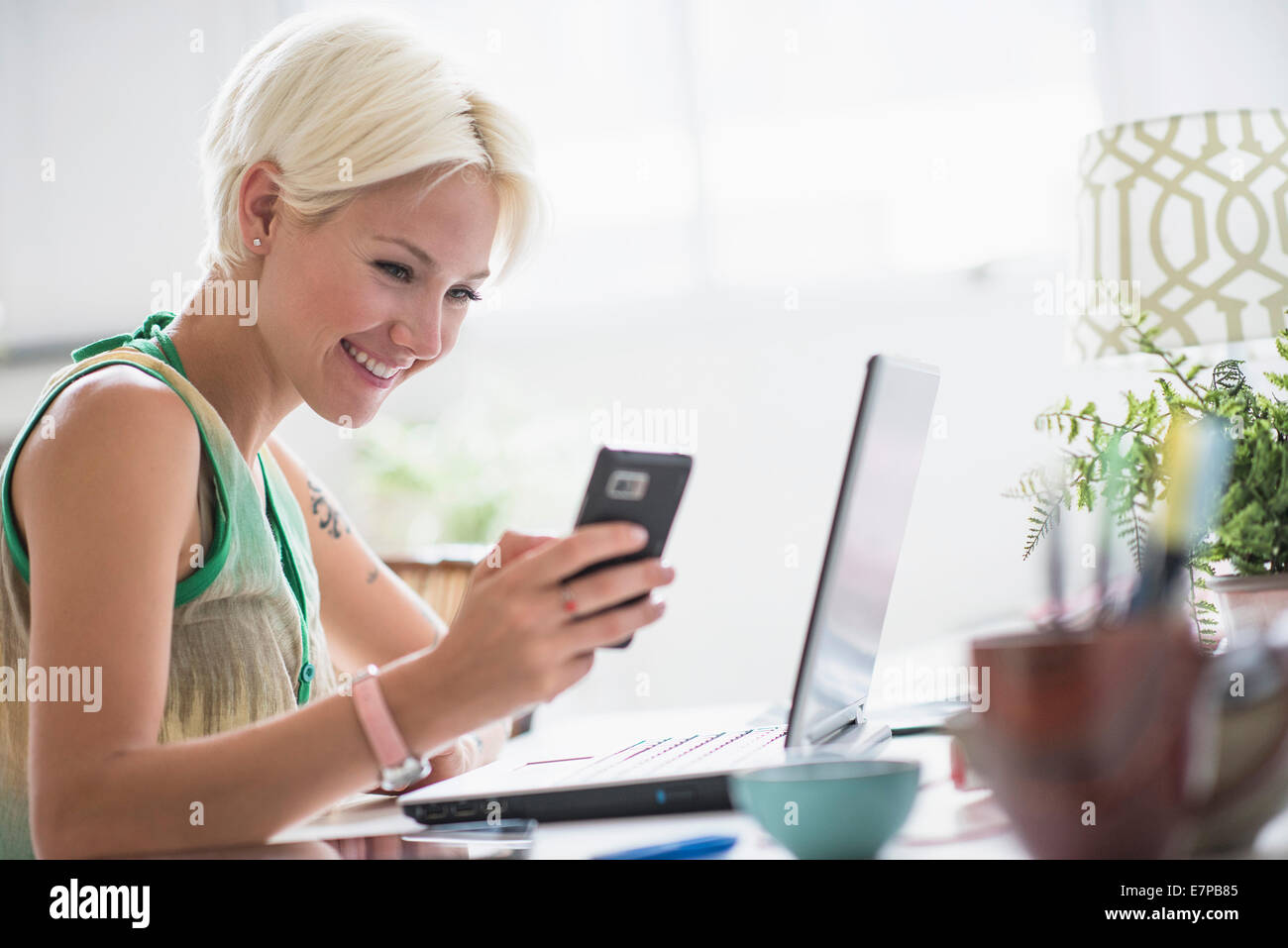 Woman using cell phone at home Banque D'Images