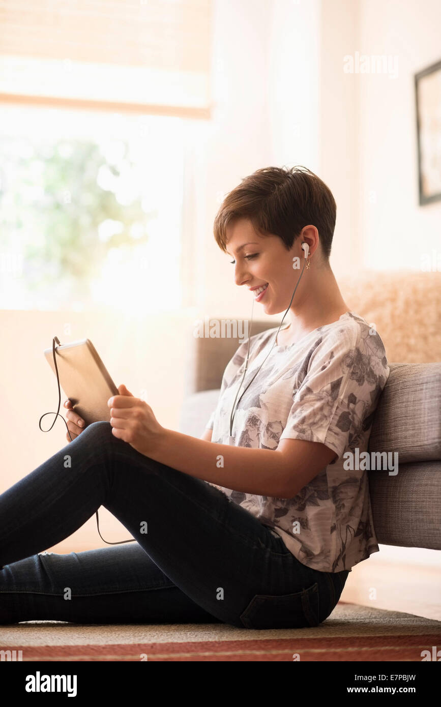 Young woman sitting on floor and using tablet pc Banque D'Images