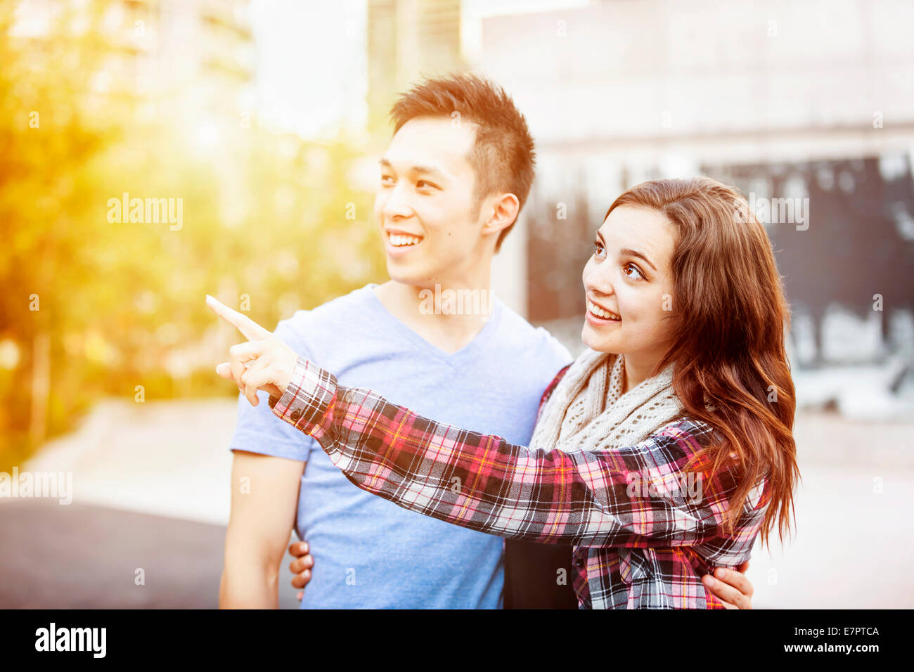 Jeune couple interracial Romantique ensemble permanent à l'extérieur de pointage dans le coucher du soleil la lumière avec des reflets intentionnelle Banque D'Images