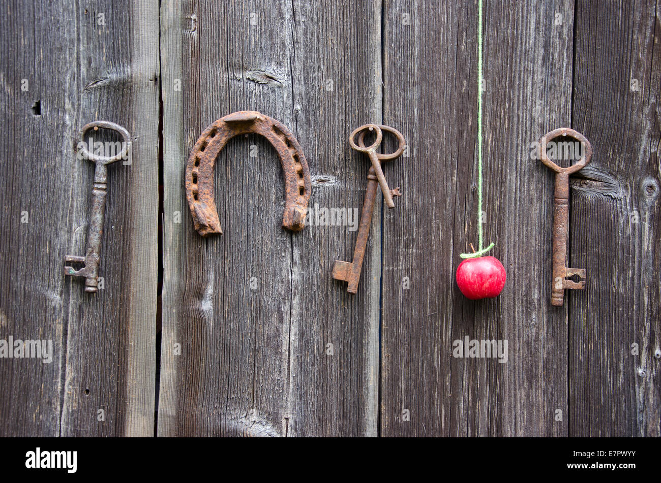 Clé ancienne, fer à cheval rouillé et pomme rouge sur l'ancien mur de la grange de ferme en bois Banque D'Images