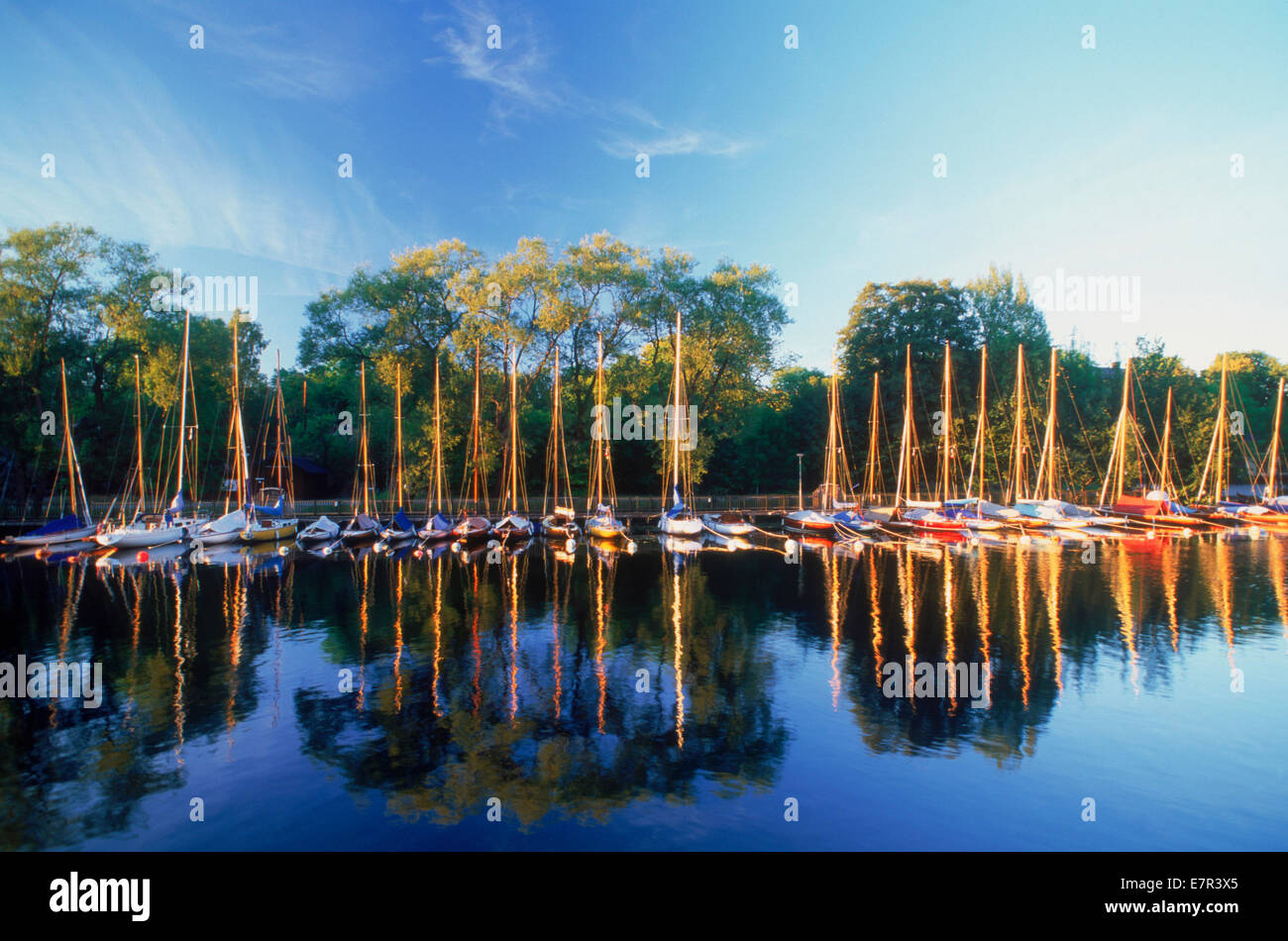 Longue rangée de voiliers amarrés au lever du soleil la lumière se reflétant sur Langholmens ou Canal Långholmen à Stockholm en Suède Banque D'Images