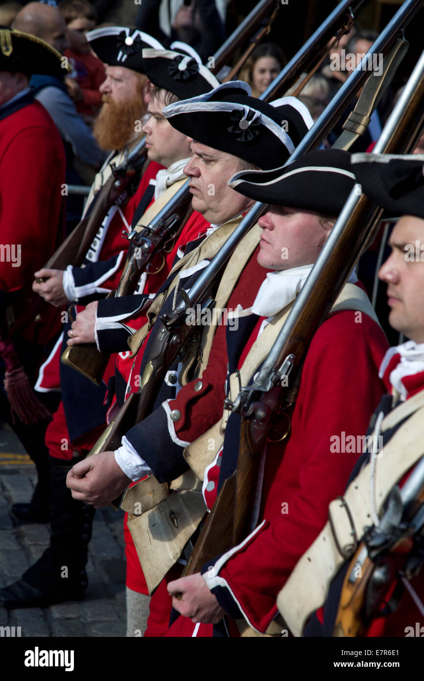 Une reconstitution historique society habillés en tuniques rouges marchant devant des foules sur le Royal Mile d'Édimbourg. Banque D'Images