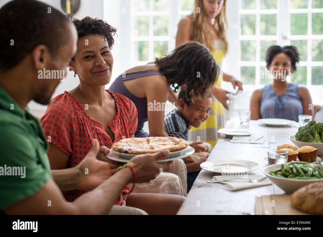 Une réunion de famille, hommes, femmes et enfants autour d'une table à manger partager un repas. Banque D'Images