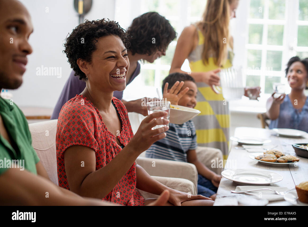 Une réunion de famille, hommes, femmes et enfants autour d'une table à manger partager un repas. Banque D'Images