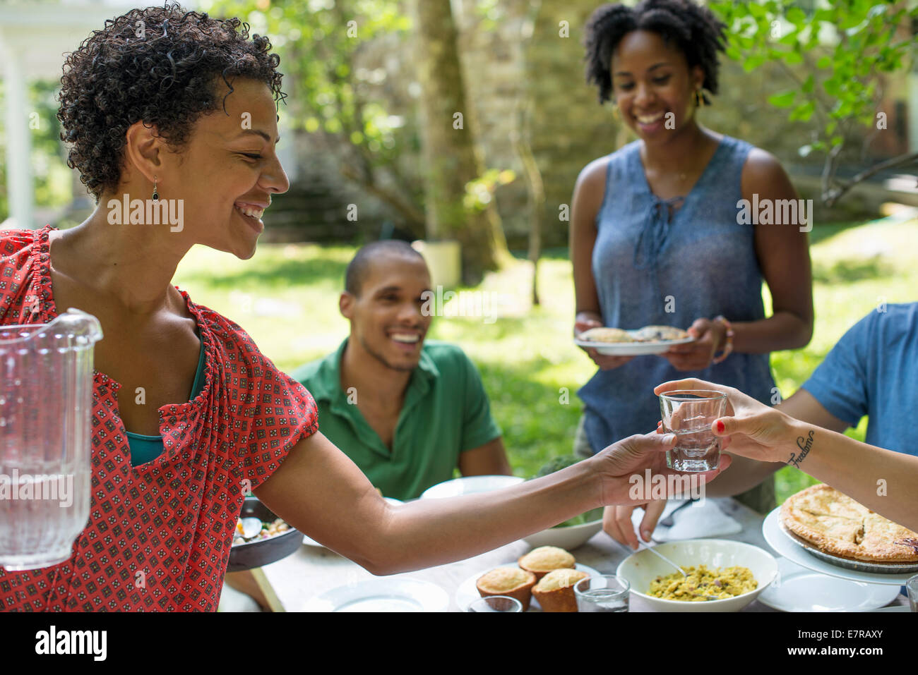 Une réunion de famille, hommes, femmes et enfants autour d'une table dans un jardin en été. Banque D'Images