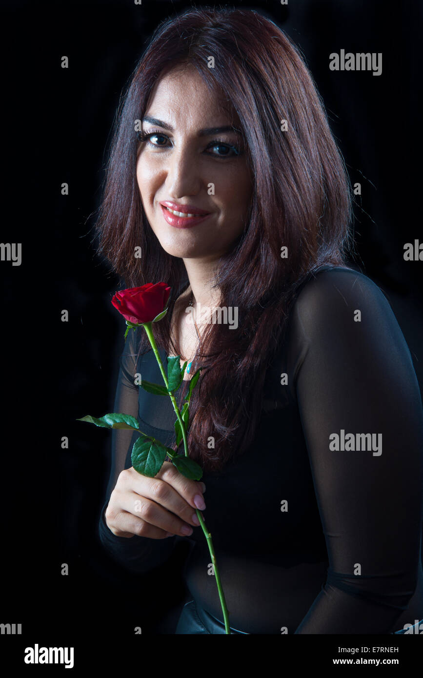 Belle brune femme tenant une rose rouge Banque D'Images