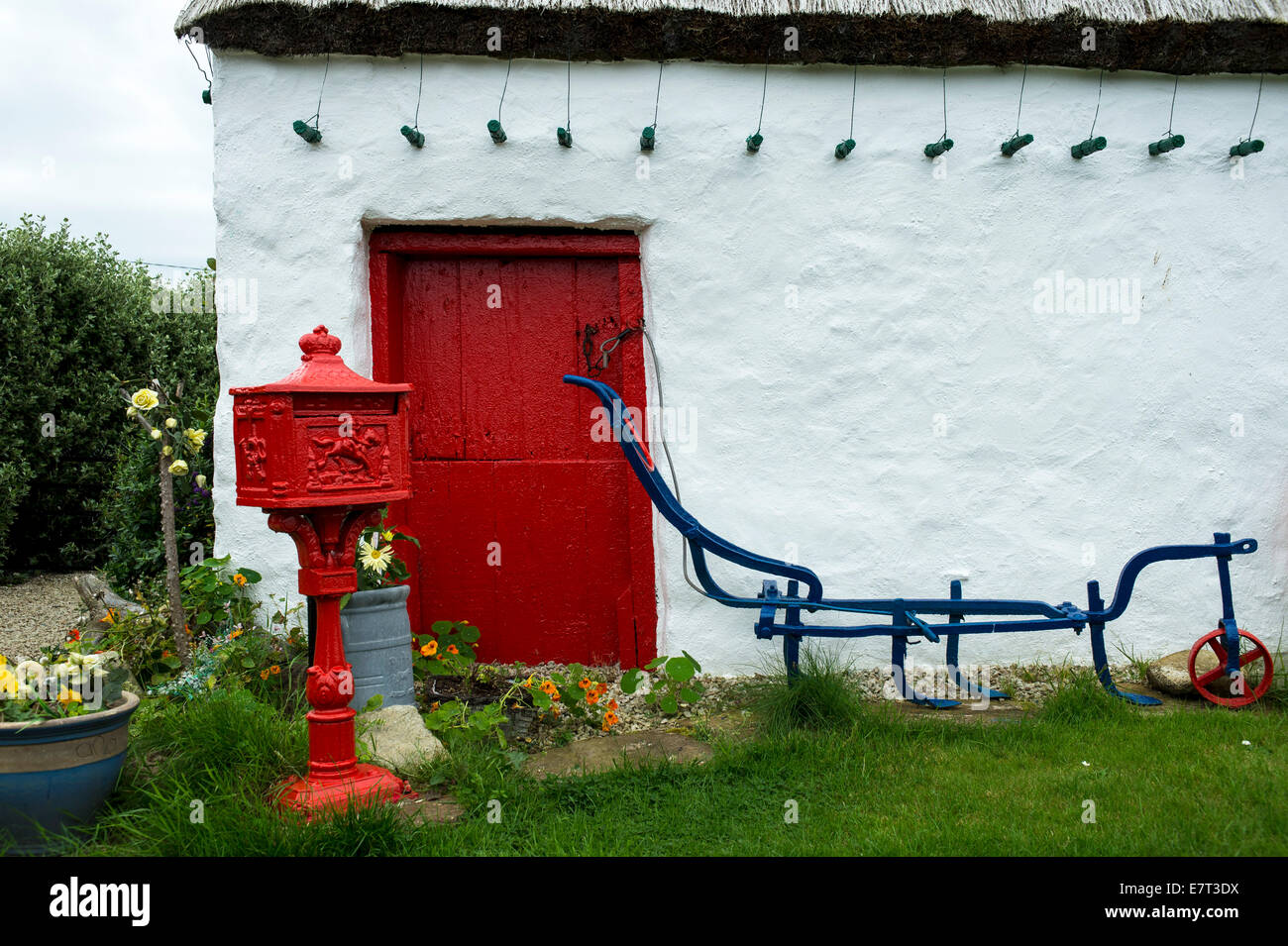 Socle rouge victorien lettre Post Box en dehors d'un irlandais traditionnel du 19ème siècle, un toit de chaume cottage, Malin Head, comté de Donegal, Banque D'Images