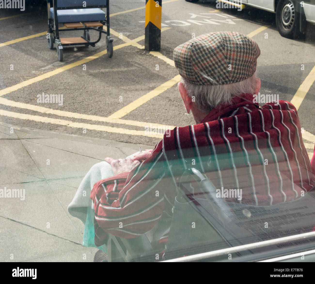 Homme âgé patient in wheelchair fumer dans la baie d'ambulance à l'extérieur de l'hôpital du NHS en Angleterre. UK Banque D'Images
