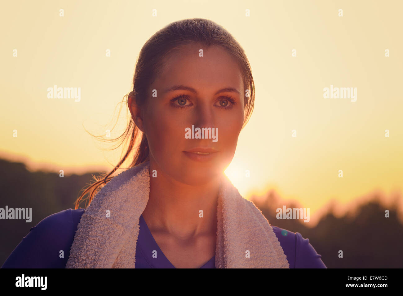Jolie femme au coucher du soleil à l'extérieur par le rétro-éclairage orangé du soleil provoquant une poussée autour de son visage Banque D'Images