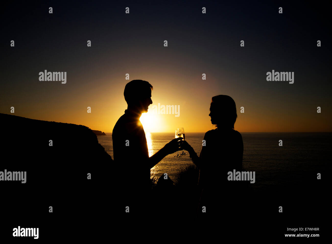 La silhouette d'un couple having drinks au coucher du soleil sur la falaise, Snug Cove, l'île kangourou en Australie Banque D'Images