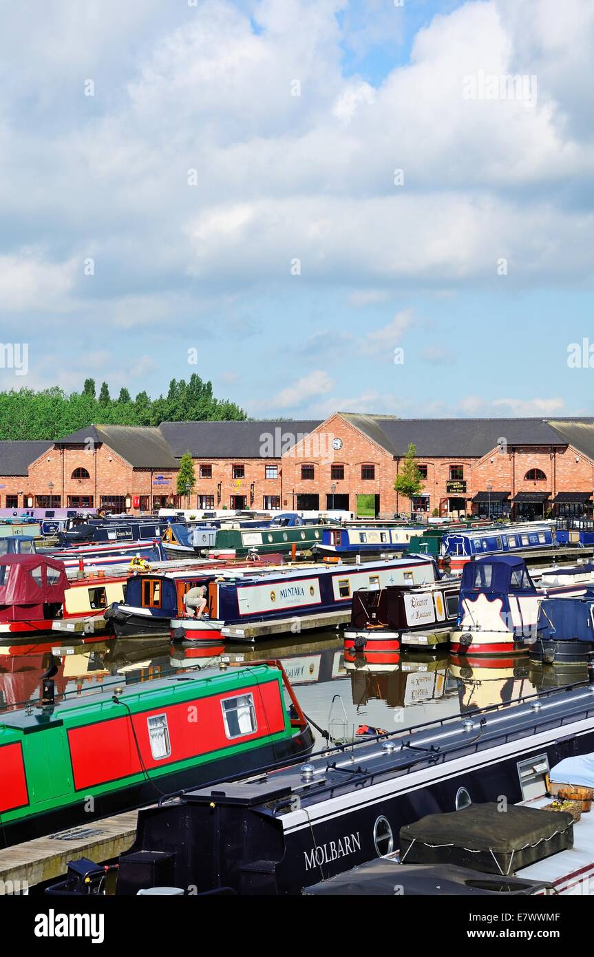 Narrowboats sur leurs amarres dans le bassin du canal, avec des magasins, bars et restaurants à l'arrière, Barton-under-Needwood, UK. Banque D'Images