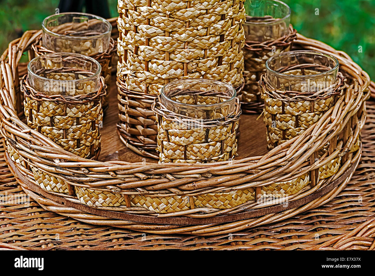 Verres et bouteille enveloppée de l'osier, placé sur un plateau et une table. Banque D'Images