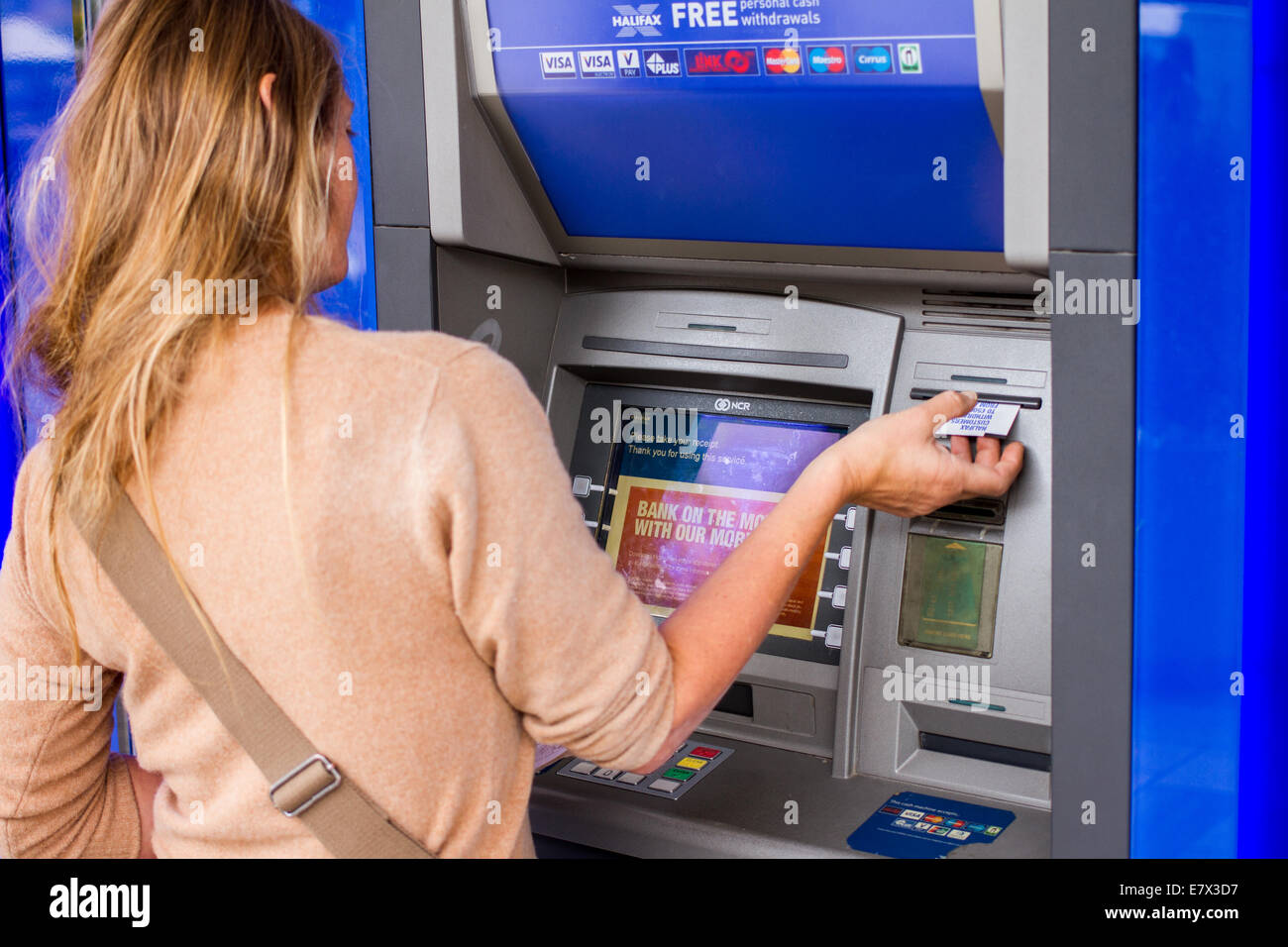 Une jeune femme à l'aide d'un distributeur de billets ATM Halifax Banque D'Images