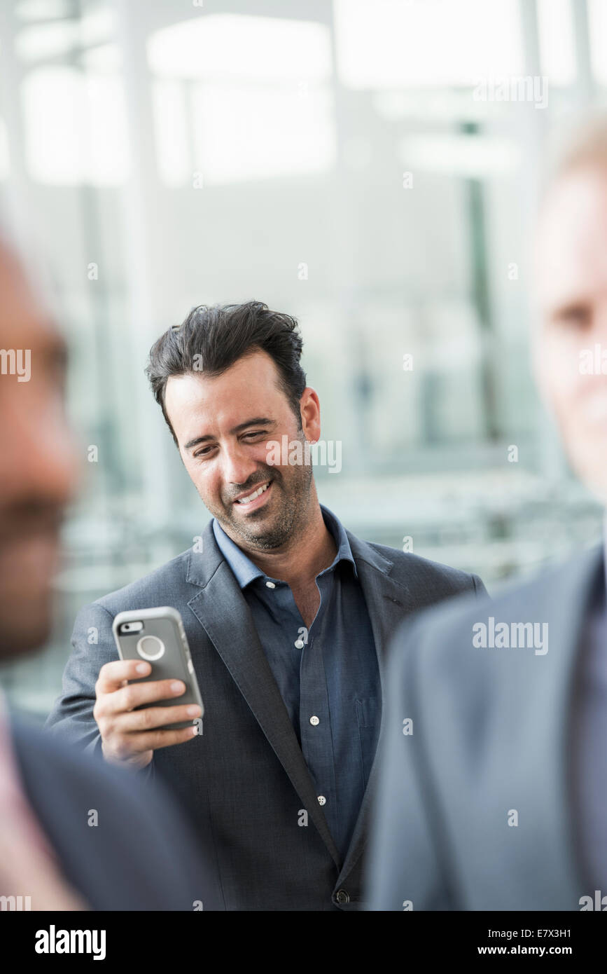Trois hommes d'affaires, un contrôle de son téléphone intelligent. Banque D'Images