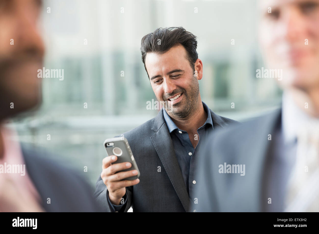 Trois hommes d'affaires, un contrôle de son téléphone intelligent. Banque D'Images