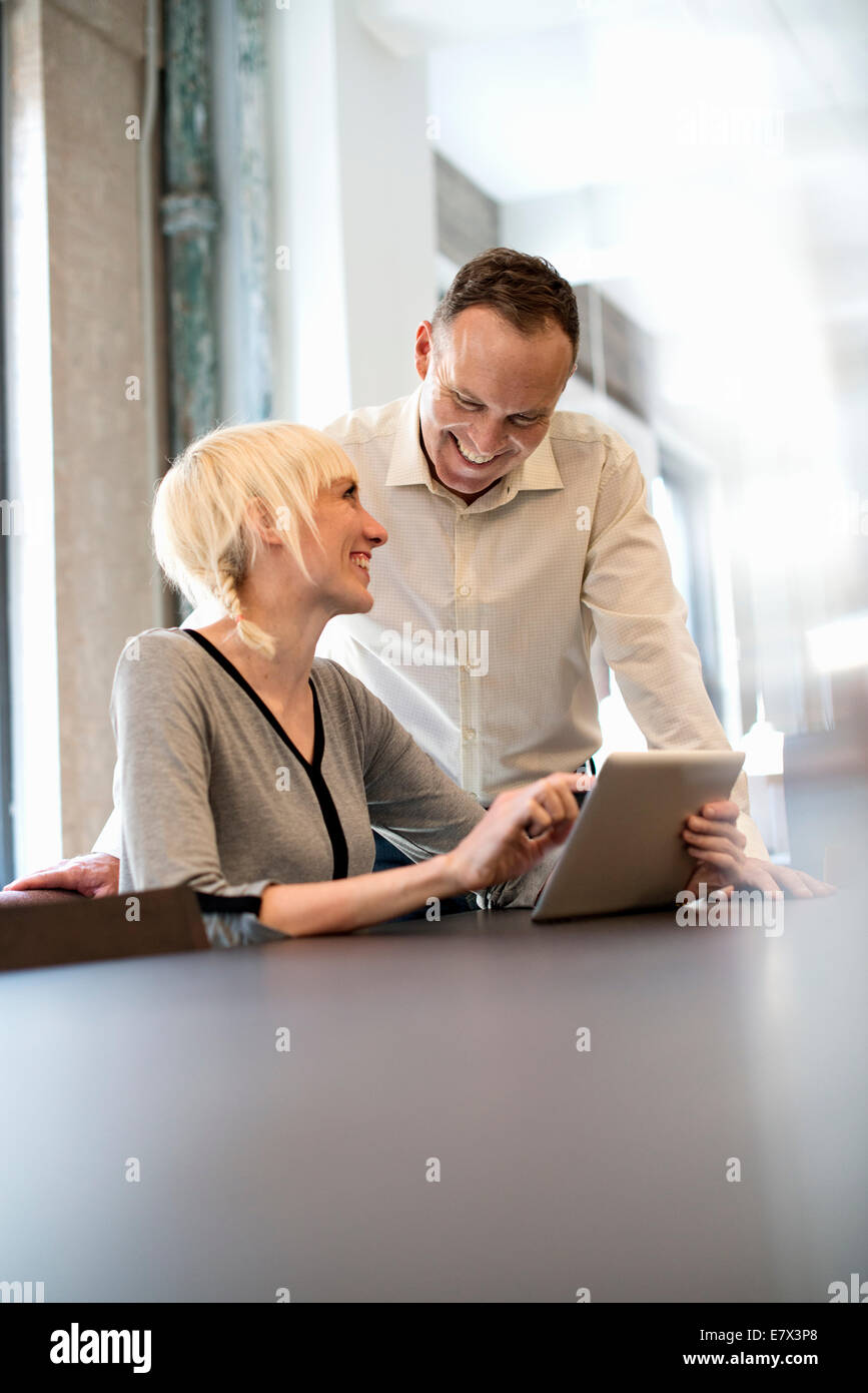 La vie de bureau. Deux personnes partageant une table numérique dans un bureau. Banque D'Images
