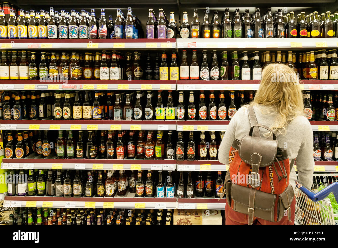 Blonde woman shopping for / acheter la bière en bouteille, supermarché Tesco, Newmarket Suffolk UK Banque D'Images