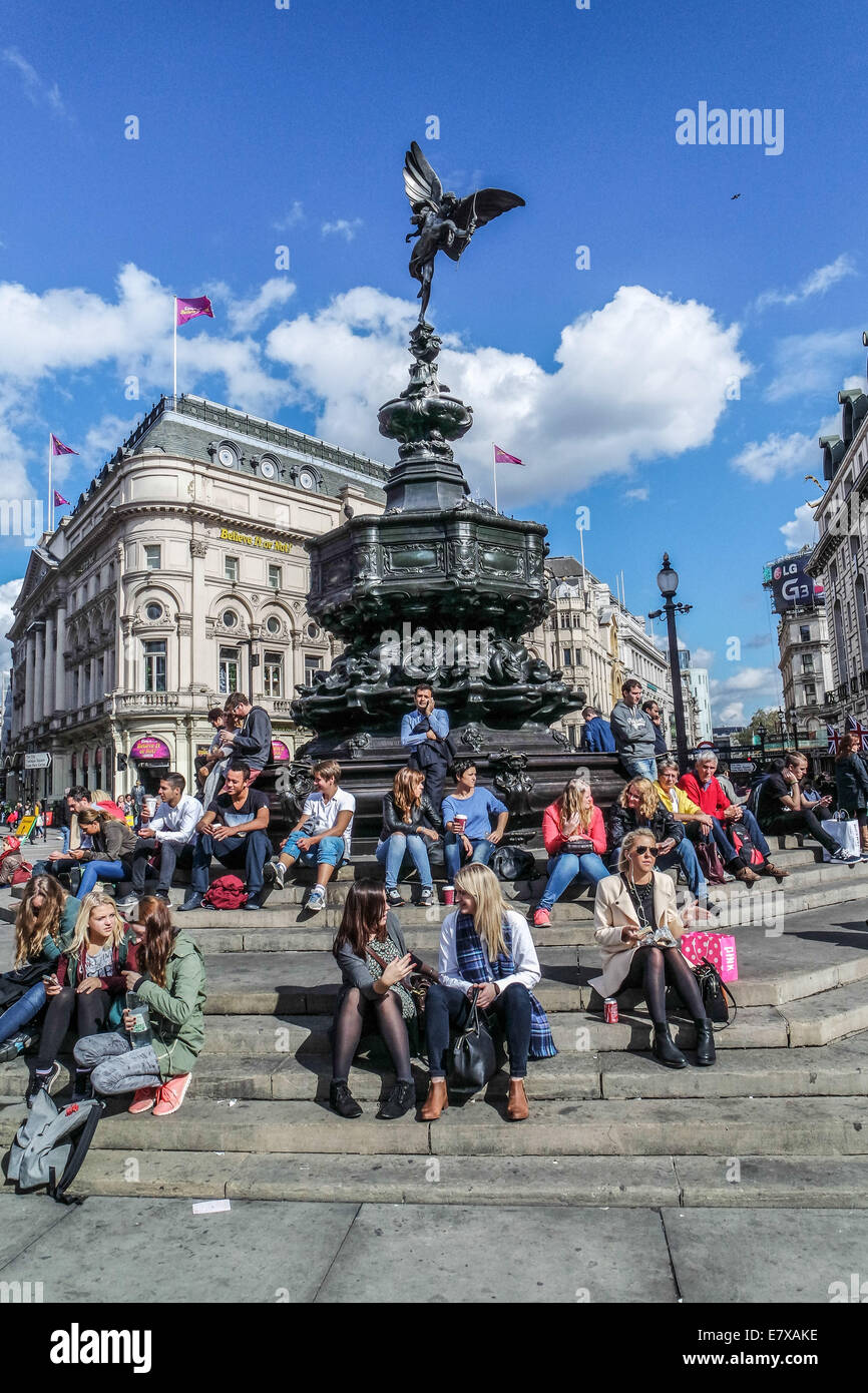 Piccadilly Circus, Londres, les touristes s'asseoir sur les marches de la statue d'Eros Banque D'Images