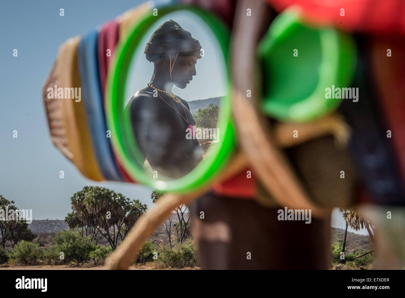 Un guerrier Samburu se reflète dans le miroir il collègues shepherd tandis que dehors qui cultivent leurs troupeaux. Les guerriers Samburu apportent leurs fl Banque D'Images