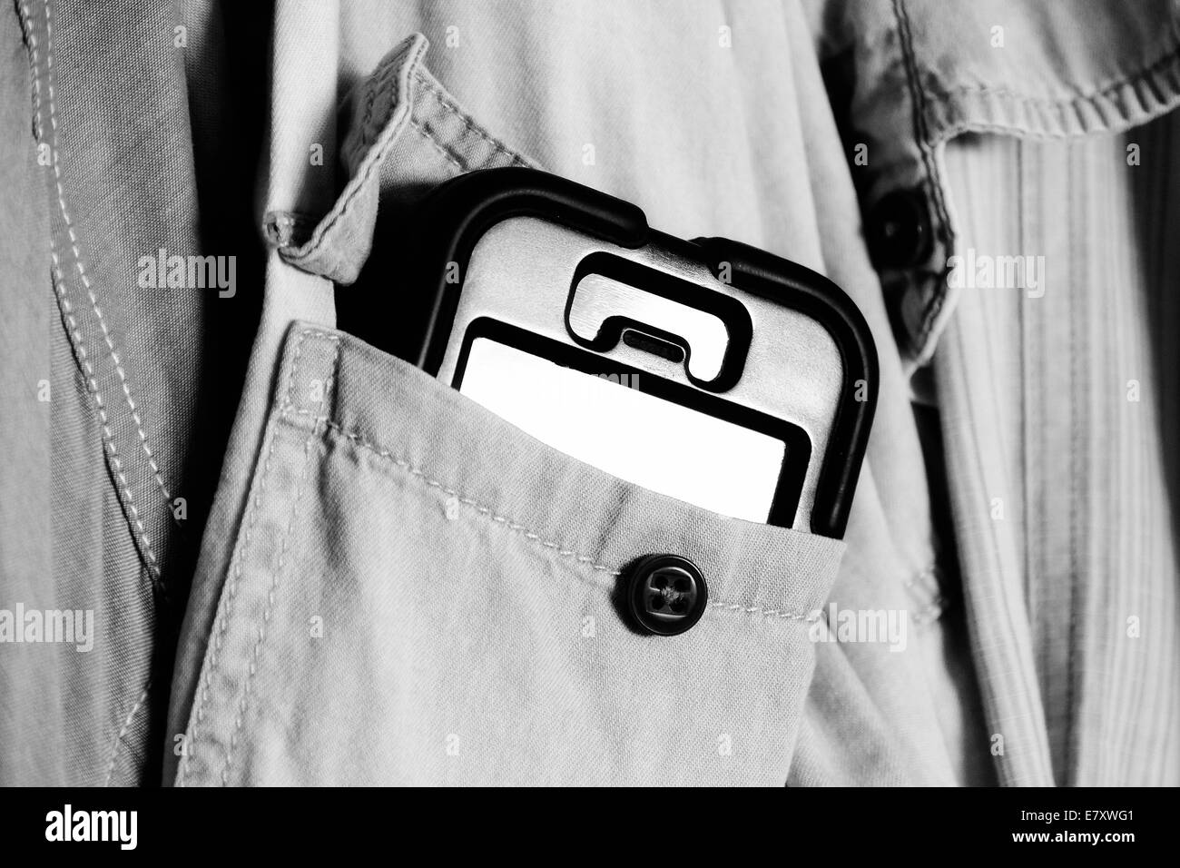 Un iphone téléphone cellulaire dans un boîtier de protection qui sort d'une poche avant shirt pendu Banque D'Images