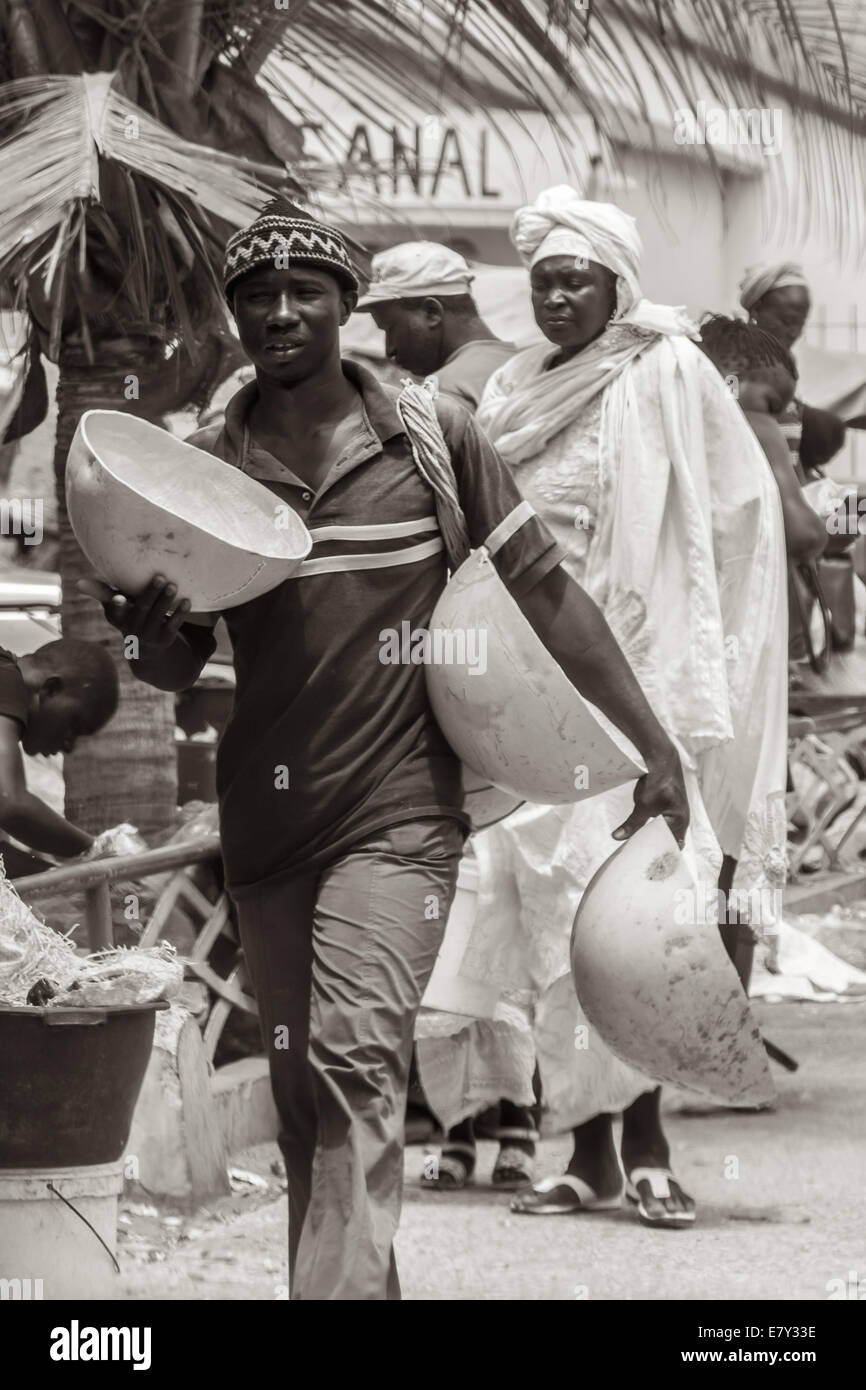 Mbour, Sénégal - Juillet 2014 : un homme porte gros bols de vendre sur les marchés de rue le 9 juillet 2014 à Mbour, au Sénégal. Banque D'Images