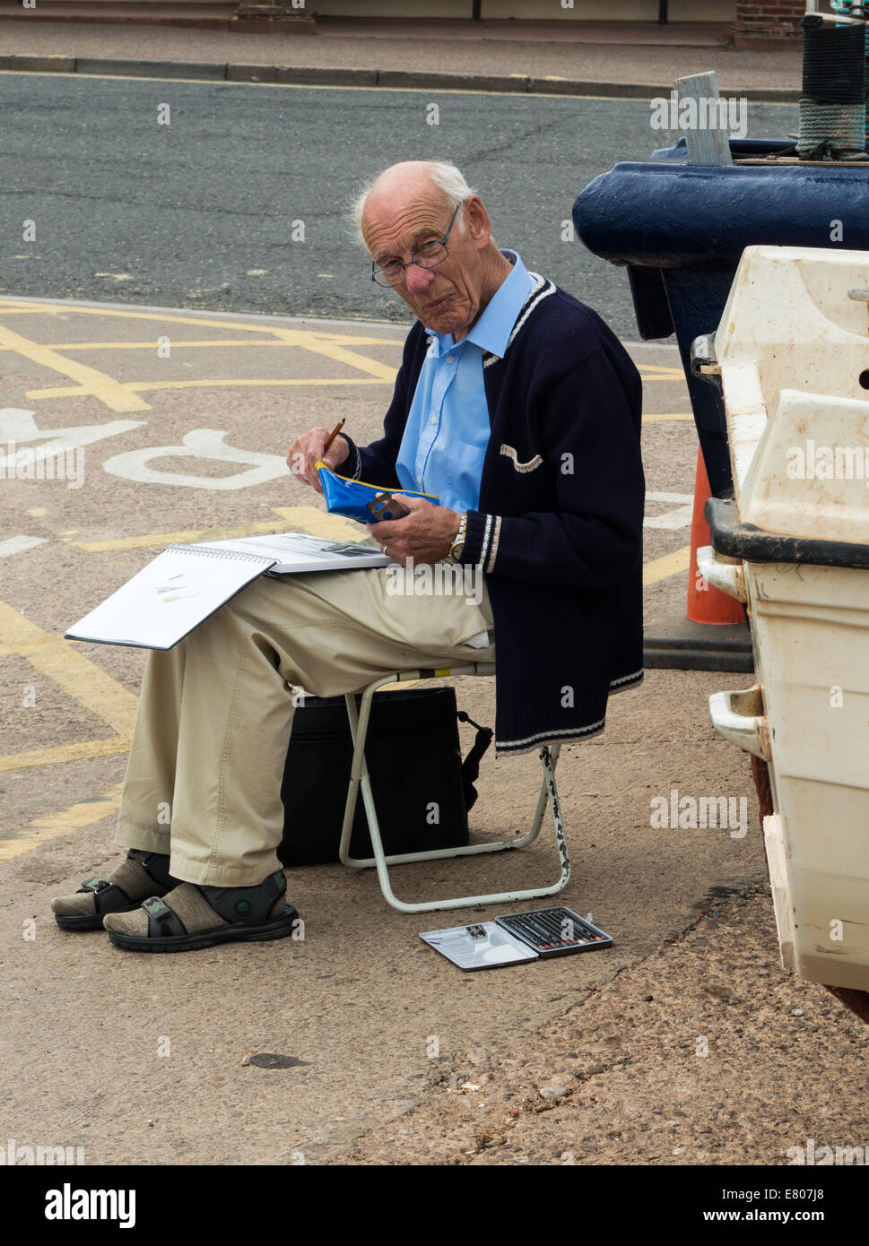 La ville de Sidmouth, Devon, Angleterre. Un homme âgé d'un croquis de l'artiste photo tout en étant assis sur un tabouret pliant dans la rue à Sidmouth. Banque D'Images